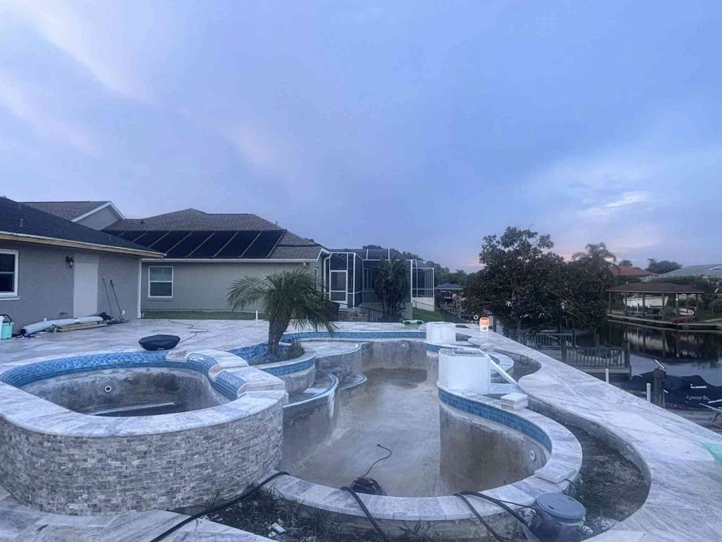 Custom luxury freeform pool with raised spa, sun deck, and fire bowls