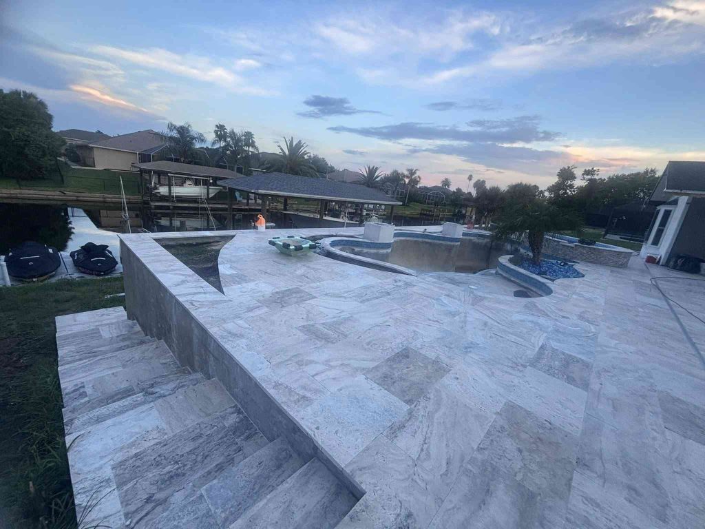 Custom luxury freeform pool with raised spa, sun deck, and fire bowls