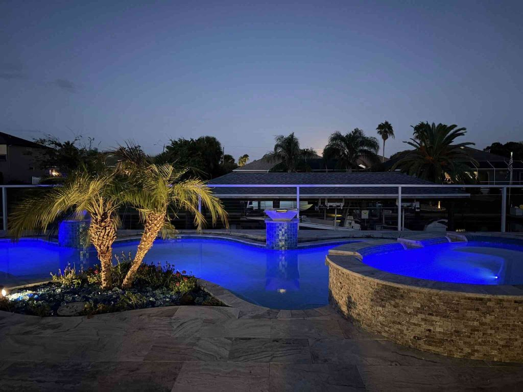 Custom luxury freeform pool with raised spa, sun deck, and fire bowls