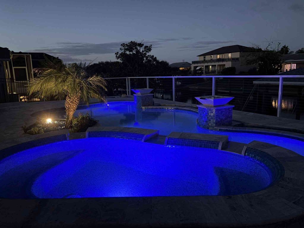 Custom luxury freeform pool with raised spa, sun deck, and fire bowls