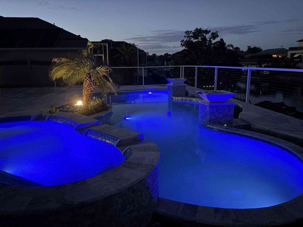 Custom luxury freeform pool with raised spa, sun deck, and fire bowls
