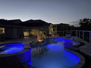 Custom luxury freeform pool with raised spa, sun deck, and fire bowls